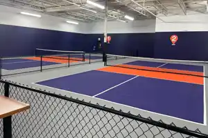 <p>Courts 1 and 2 at Pickleplex in Barrie, ON—part of a seven-court indoor pickleball facility. This photo showcases the bright orange and purple color scheme and perimeter fencing designed for dedicated play zones.</p>